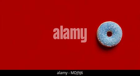 Avec anneau bleu avec noix de coco râpée isolé sur un fond rouge. Banque D'Images