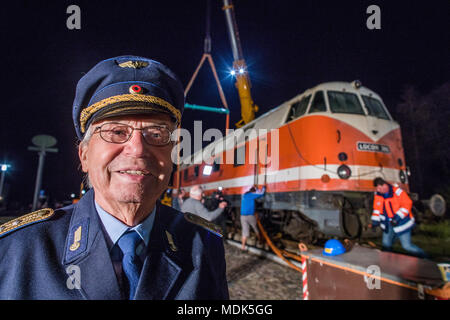 19 avril 2018, l'Allemagne, Peter conducteur de locomotive : Gadebusch Falow sourit dans son vieux Reichsbahn uniforme que deux grues ascenseur une 78 tonne locomotive diesel du modèle V-180 dans le musée ferroviaire à l'extérieur de la gare locale. La soi-disant 'cigare' locomotive a été construit en 1967. Photo : Jens Büttner/dpa-Zentralbild/dpa Banque D'Images