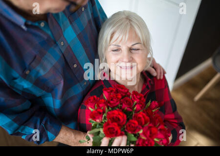 Cropped portrait of senior man giving son épouse bouquet de roses Banque D'Images