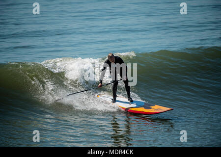 19.04.18. Météo de Bournemouth. Une pagaie boarder surfe sur une vague à côté de la jetée de Bournemouth car les températures montent sur la côte sud du Royaume-Uni. Banque D'Images