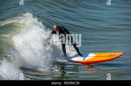 19.04.18. Météo de Bournemouth. Une pagaie boarder surfe sur une vague à côté de la jetée de Bournemouth car les températures montent sur la côte sud du Royaume-Uni. Banque D'Images