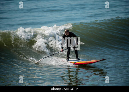 19.04.18. Météo de Bournemouth. Une pagaie boarder surfe sur une vague à côté de la jetée de Bournemouth car les températures montent sur la côte sud du Royaume-Uni. Banque D'Images