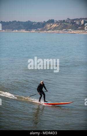 19.04.18. Météo de Bournemouth. Une pagaie boarder surfe sur une vague à côté de la jetée de Bournemouth car les températures montent sur la côte sud du Royaume-Uni. Banque D'Images