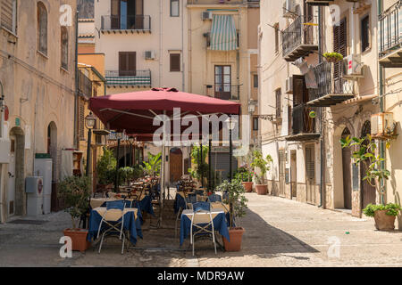 Table et chaises à l'extérieur d'un restaurant, L'Antica Corte, de Cefalù, Sicile, Italie sur une journée d'été ensoleillée en août. Banque D'Images