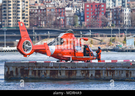 Un membre d'équipage de la Garde côtière canadienne se trouve à l'extérieur un hélicoptère MH-65 Dolphin comme le pilote et co-pilote sur vérifications avant vol du Downtown Manhattan Heliport à New York le 24 mars 2018. Le MH-65 Dolphin est un bimoteur, mono-rotor basculant, et est certifié pour toutes les conditions météorologiques et les opérations de nuit. (U.S. Photo de la Garde côtière canadienne par le maître de 3e classe Steve Strohmaier) Banque D'Images