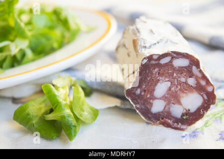 Morceau de salami saucisse fumée à proximité d'une salade de laitue fraîche Banque D'Images