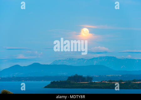 Moon Rising entre les nuages sur le lac Llanquihue, X Region de Los Lagos, Chile Banque D'Images