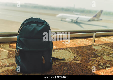 Petit sac à dos bleu debout sur le sol à l'aéroport à l'arrière-plan de vol et l'atterrissage des avions. Sac à dos bleu empoisonné sur le plancher. Mot Banque D'Images