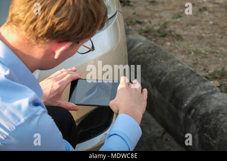 L'agent Young man holding smart phone pour prendre une photo de voiture ventilées par accident de la circulation pour demander l'assurance automobile. Banque D'Images