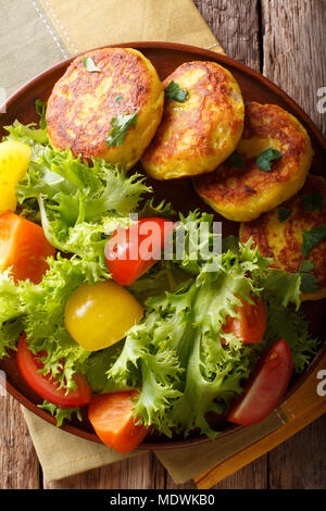 Llapingachos équatorienne les galettes de pommes de terre et salade fraîche close-up sur une plaque sur une table. Haut Vertical Vue de dessus Banque D'Images