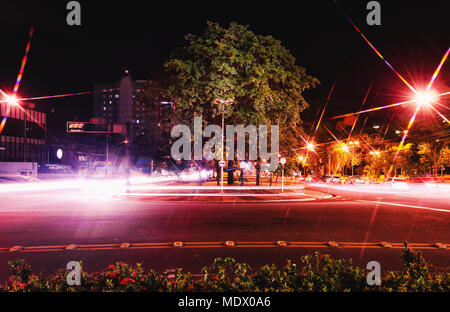 Le trafic urbain la nuit. Colorful longue exposition photo de voitures sur une grande avenue de deux façons, le centre de trottoir avec de grands arbres. Le trafic à Afonso P Banque D'Images