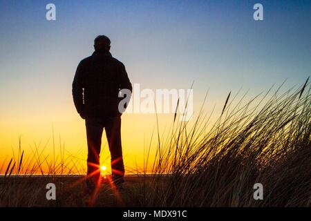 Magnifique Coucher de soleil, Southport, Merseyside. 20 avril 2018. Météo britannique. Un homme se tient sur les dunes de sable regardant le coucher de soleil tombe dans l'horizon sur la plage de Southport Merseyside. Credit : Cernan Elias/Alamy Live News Banque D'Images