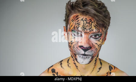 Portrait d'un homme peint comme un tigre sur un fond gris. coloriage visage Banque D'Images