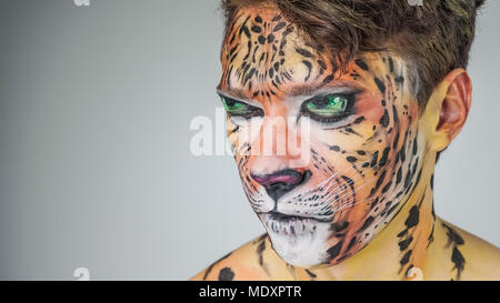 Portrait d'un homme peint comme un tigre sur un fond gris. coloriage visage Banque D'Images