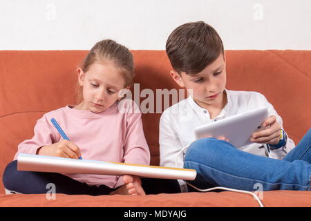 Deux enfants qui jouent, un avec le livre à colorier et les autres avec la tablette numérique Banque D'Images