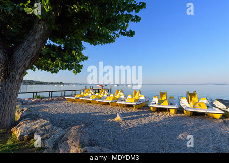 Rangée de pédalos colorés sur la plage le matin sur le lac de Garde (Lago di Garda) à Bardolino en Vénétie, Italie Banque D'Images