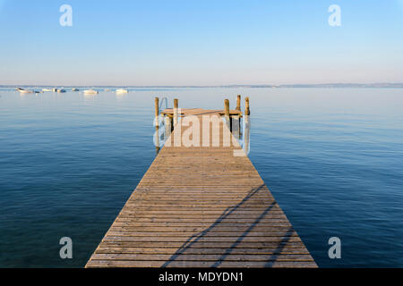 Jetée en bois sur le lac de Garde (Lago di Garda) sur un matin ensoleillé à Bardolino en Vénétie, Italie Banque D'Images