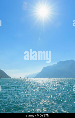 Planche à voile sur le lac de Garde avec avec soleil dans le ciel bleu à Torbole en Trentin, Italie Banque D'Images