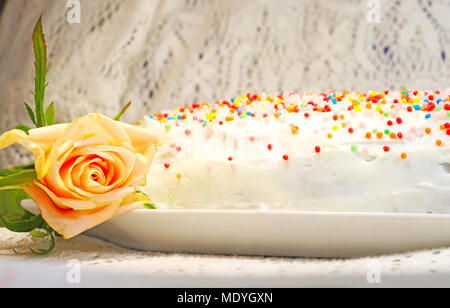 Un livre blanc gâteau décoré avec des bonbons colorés sur un plateau sur une table avec une nappe en dentelle Banque D'Images