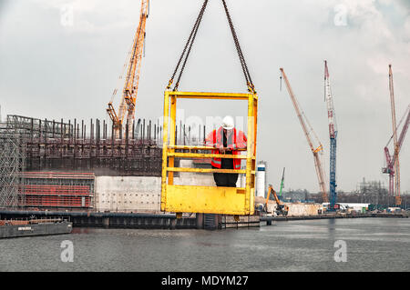 Travailleur de la construction est dans une cage au-dessus du jaune du canal de levage Banque D'Images