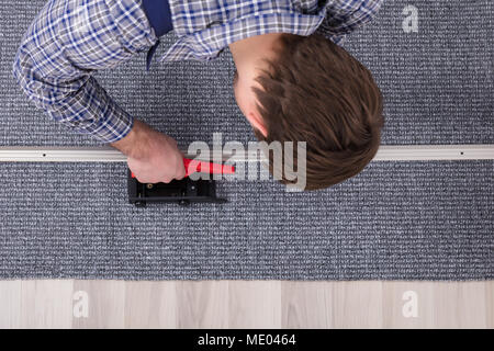 Close-up d'un ajusteur de Tapis Tapis gris la main de l'installation avec tournevis sans fil Banque D'Images