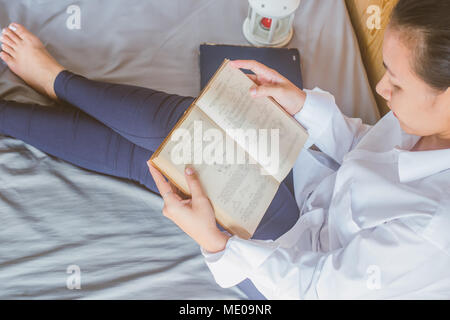 Soft image de jeune femme Asain texte lecture livre sur son lit dans la chambre Banque D'Images