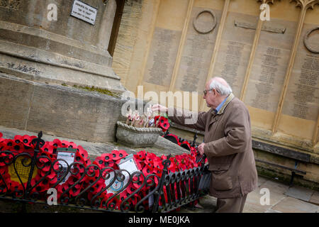 Homme âgé met une petite croix sur Cirencester War Memorial est ensuite et se rappelle le passé en regardant les coquelicots et couronnes Banque D'Images