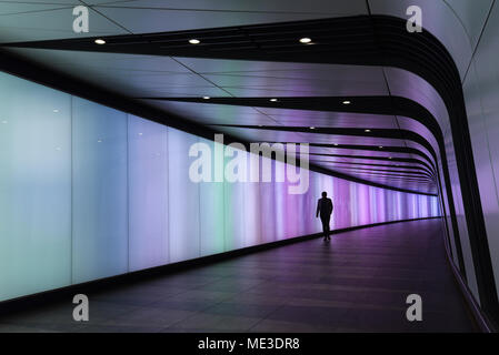 Silhouette d'homme marchant à travers un tunnel éclairé Banque D'Images