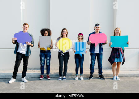 Young adult friends holding up copyspace placard bulles Banque D'Images