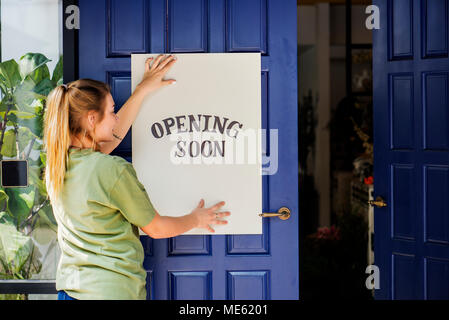 Woman putting on store ouverture bientôt signer Banque D'Images