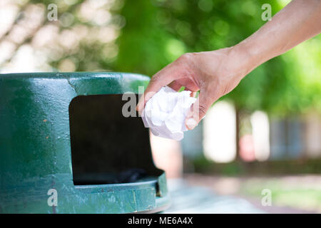 Portrait d'une personne cultivée Gros plan tossing feuille de papier froissé dans la corbeille, isolé à l'extérieur des arbres verts contexte Banque D'Images