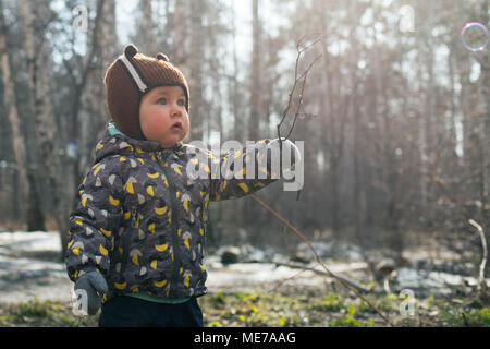 L'enfant joue émotionnellement avec une brindille, la magie et le charme de la forêt. Sans les feuilles de la forêt au printemps ou en automne. Banque D'Images