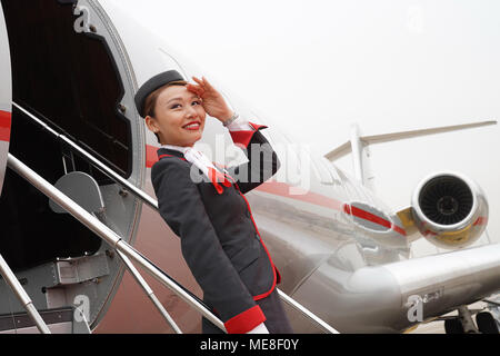 Beijing, Chine. Apr 16, 2018. Un exposant pose pour des photos en face d'un aéronef à afficher dans l'Asian Business Aviation Conference and Exhibition (ABACE) à l'Aéroport International de Shanghai Hongqiao de Shanghai, en Chine orientale, le 16 avril 2018. L'ABACE devrait avoir lieu ici du 17 au 19 avril, a attiré plus de 170 entreprises à travers le monde de participer à l'exposition. Crédit : Chen Fei/Xinhua/Alamy Live News Banque D'Images