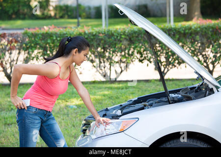Closeup portrait, jeune femme en rose tanktop des ennuis avec sa voiture cassée, l'ouverture de capot et à la recherche à moteur pour voir quoi de mal isolés, gree Banque D'Images