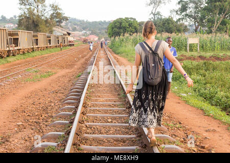 Lugazi, en Ouganda. 17 mai 2017. Une fille à la peau blanche (appelé 'mzungu' ou 'Muzungu' par les habitants) est la marche et en équilibre sur un rail sur une voie de chemin de fer. Banque D'Images