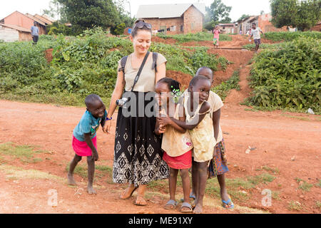 Lugazi, en Ouganda. 17 mai 2017. Un bénévole à peau blanche (appelé 'mzungu' ou 'Muzungu' localement) holding hands with enfants ougandais dans une zone rurale. Banque D'Images