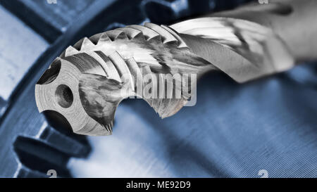 Touchez à goujure hélicoïdale et Chuck avec copie espace. Close-up artistique de l'outil de coupe en acier argenté avec filetage métallique bleu roue dentée sur l'arrière-plan. Banque D'Images