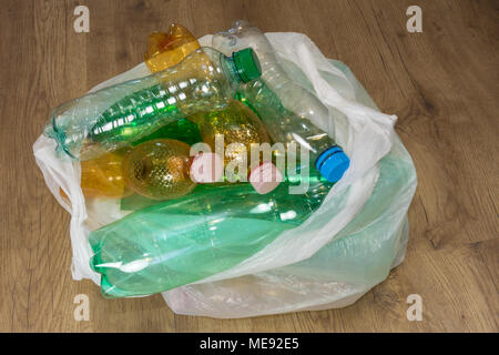 Les bouteilles en PET vides sur le plancher de bois. La séparation écologique des ordures ménagères. Les déchets de plastique dans un sac. Vue de dessus. Banque D'Images