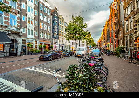 Une rue typique d'Amsterdam au large de la région du canal principal avec les vélos et les voitures garées devant les magasins au début de l'automne Banque D'Images