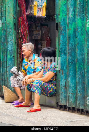 Deux femmes âgées l'un et l'autre moyen-âge assis dans l'embrasure d'avoir une conversation tranquille à Ho Chi Minh City, Vietnam. Banque D'Images