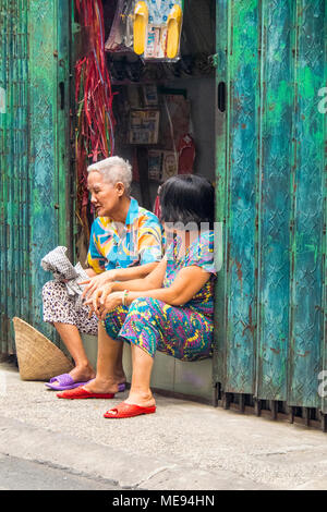 Deux femmes âgées l'un et l'autre moyen-âge assis dans l'embrasure d'avoir une conversation tranquille à Ho Chi Minh City, Vietnam. Banque D'Images