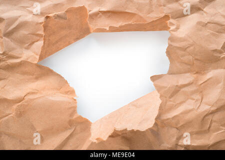 Trou dans le papier kraft brun feuille avec bords déchirés. Centre blanc isolé, chemin de détourage inclus Banque D'Images