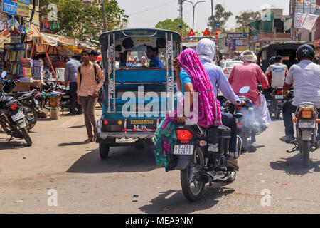 Scène de rue à Dausa, Rajasthan, Inde du nord, une femme de la région à cheval sur une moto avec leurs couleurs locales typiques et vêtements Coiffure voile Banque D'Images