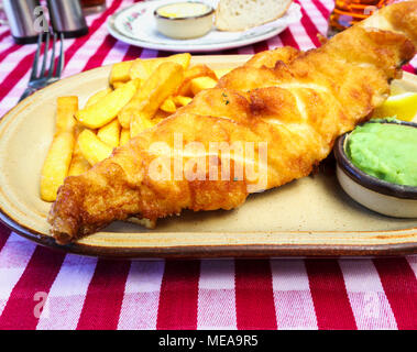 Poisson battues (bière batter), Golden Chips, petits pois déjeuner ou dîner : plaque de pub anglais traditionnel de la nourriture sur une case rouge et blanc nappe Vichy Banque D'Images