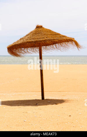 Parasol de paille sur une plage de sable. Banque D'Images