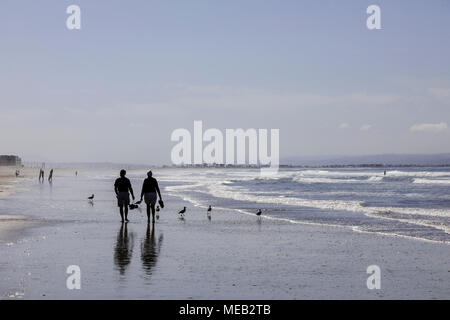 Mature couple marchant le long de la plage, portant leurs chaussures. Banque D'Images