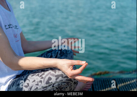 Close up of a woman practicing yoga à côté de l'eau, la méditation et la détente. Banque D'Images