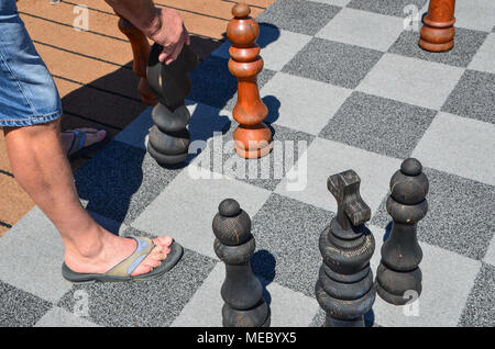 L'homme se déplace sur de grandes pièces d'échecs plateau d'échec en plein air. Jeu de stratégie, comme l'homme jouant aux échecs sur l'extérieur géant se déplace, Knight Banque D'Images