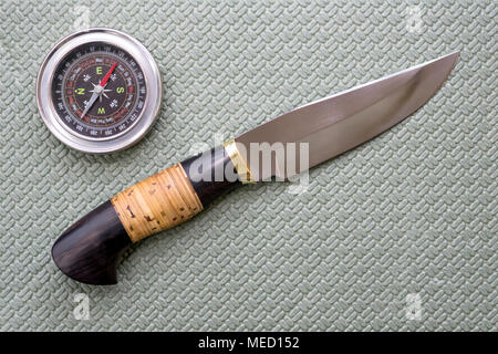 Un couteau de chasse et d'une boussole s'allonger sur un tapis de tourisme. L'équipement pour le voyage. Banque D'Images
