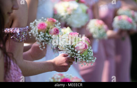 Une jeune mariée et demoiselles en robes rose tenant leurs bouquets. Banque D'Images